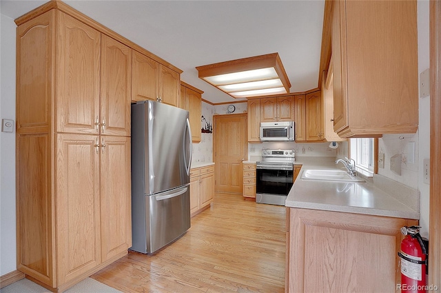 kitchen featuring light wood-type flooring, sink, appliances with stainless steel finishes, and light brown cabinetry