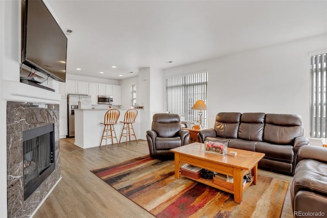 living room with light wood-type flooring, a wealth of natural light, and a premium fireplace