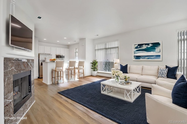 living room with light wood-style flooring, a fireplace, a wealth of natural light, and recessed lighting