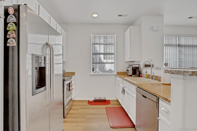 kitchen with stainless steel appliances, a sink, visible vents, white cabinets, and light wood finished floors