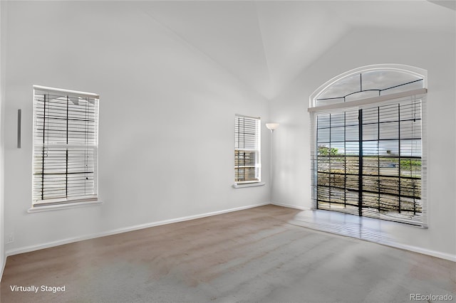 spare room featuring high vaulted ceiling and baseboards