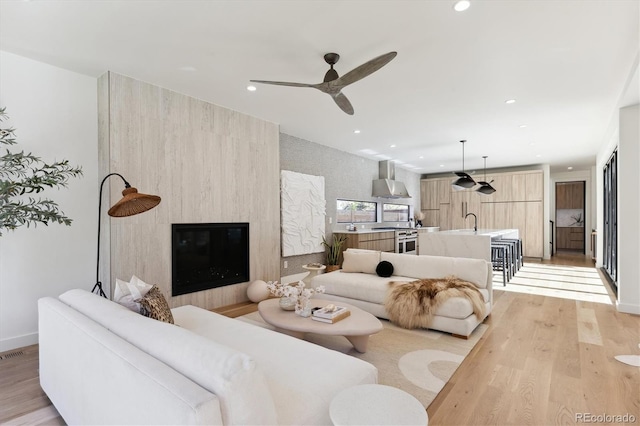 living room featuring ceiling fan, sink, and light hardwood / wood-style floors