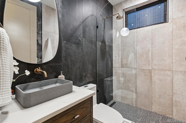 bathroom with a tile shower, tile walls, and toilet