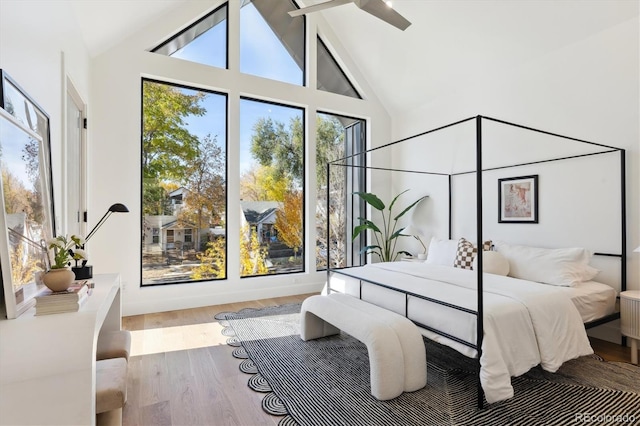 bedroom with light wood-type flooring, high vaulted ceiling, and ceiling fan