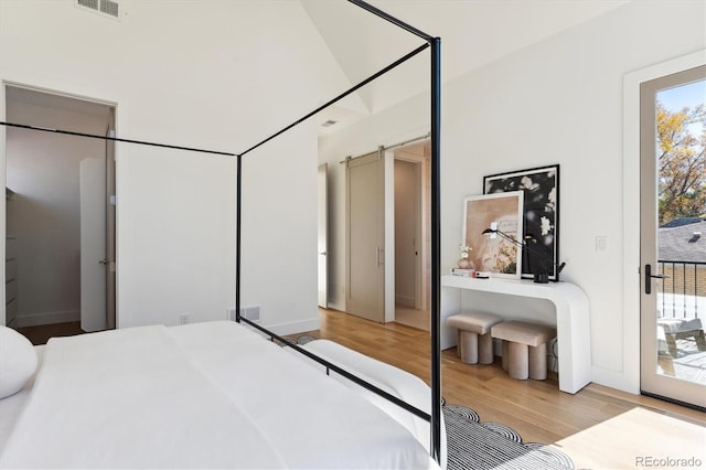 bedroom featuring light hardwood / wood-style floors, a barn door, and access to outside