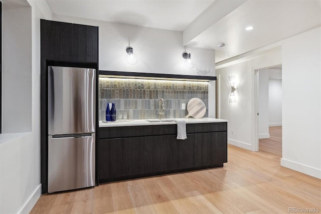 kitchen with light wood-type flooring, stainless steel refrigerator, and sink