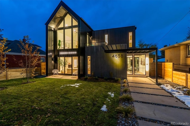 back house at night featuring a yard and a patio