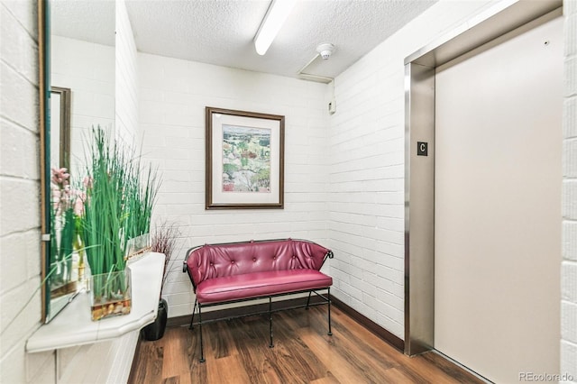 725 S Alton Way Unit 9C, Denver, CO 80247 - living area with wood finished floors, a textured ceiling, brick wall, and elevator