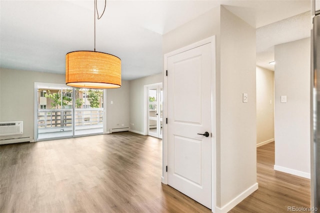 725 S Alton Way Unit 9C, Denver, CO 80247 - unfurnished room with wood finished floors, baseboard heating, and a wall mounted air conditioner
