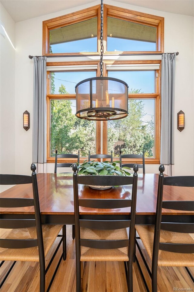 dining room with hardwood / wood-style flooring, vaulted ceiling, and an inviting chandelier