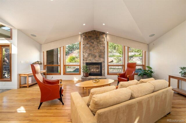 living room with light hardwood / wood-style floors, lofted ceiling, a stone fireplace, and radiator