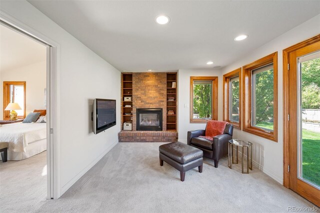 living room featuring light carpet, a fireplace, and built in shelves