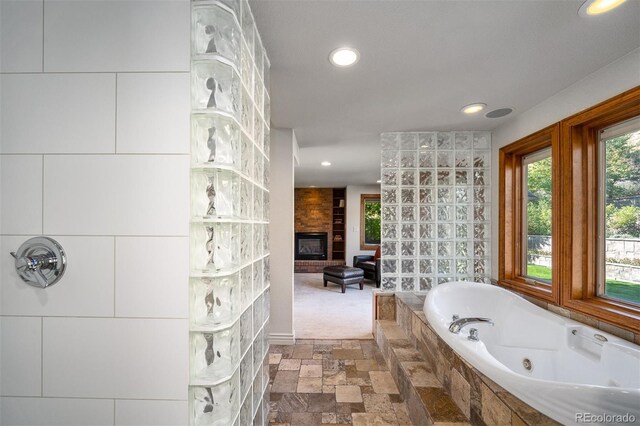 bathroom with a fireplace and tiled tub