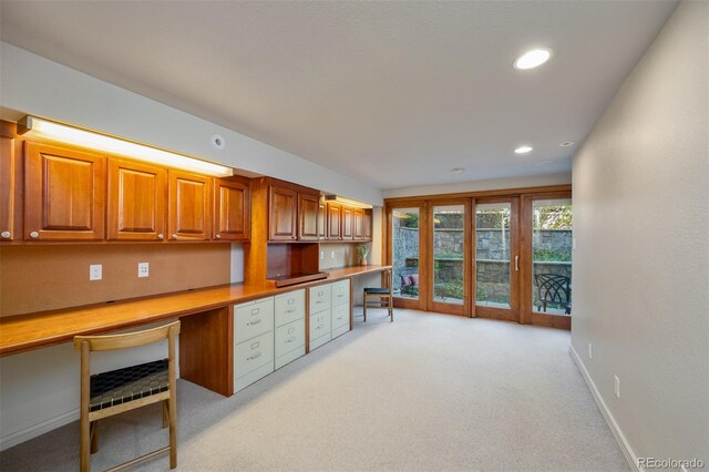 kitchen with built in desk and light colored carpet