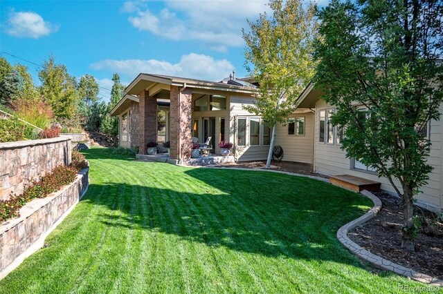 rear view of property featuring a patio and a lawn