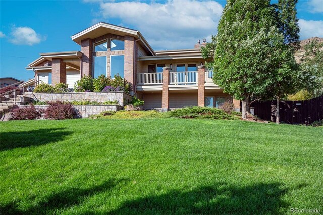 back of property with a balcony and a lawn