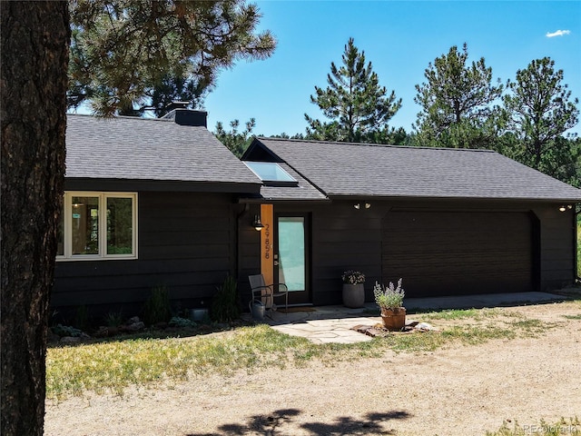 29858 Gigi Dr, Evergreen, CO 80439 - view of front of home featuring a shingled roof, a chimney, a garage, and dirt driveway