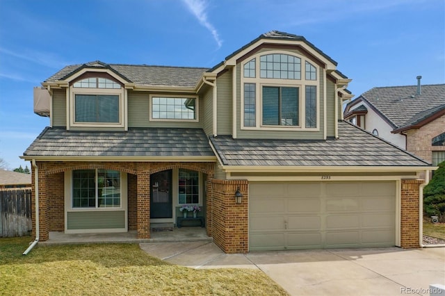 view of front facade featuring brick siding, covered porch, concrete driveway, and a front yard