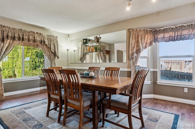 dining space with visible vents, wood finished floors, baseboards, and a textured ceiling