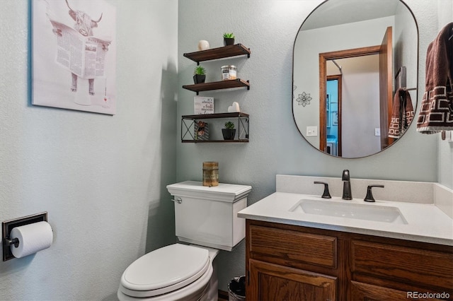 half bath with toilet, vanity, and a textured wall