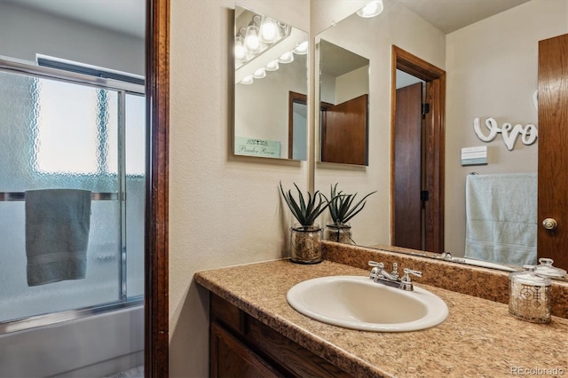 bathroom featuring combined bath / shower with glass door and vanity