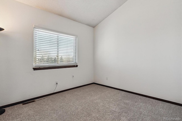 unfurnished room with vaulted ceiling, carpet flooring, and baseboards