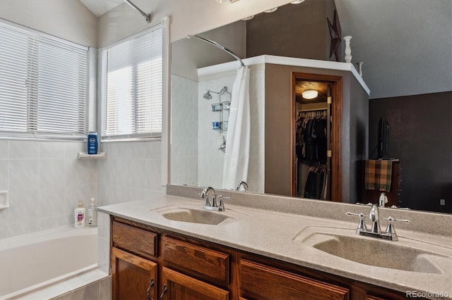 bathroom featuring double vanity, a tub, a tile shower, and a sink