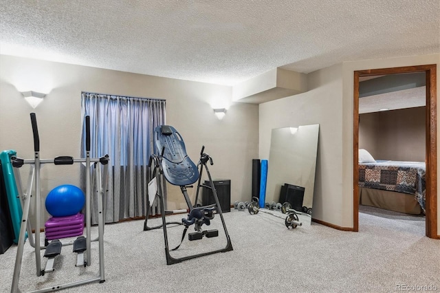 exercise area featuring baseboards, carpet floors, and a textured ceiling