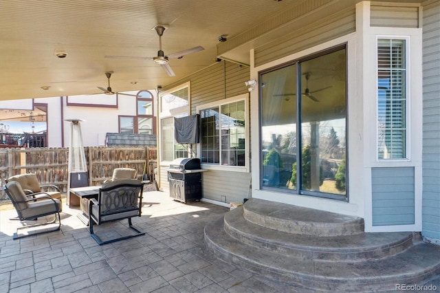 view of patio featuring a grill, ceiling fan, and fence