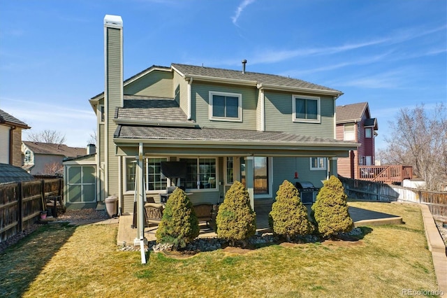 back of house with an outbuilding, a lawn, a fenced backyard, and a chimney