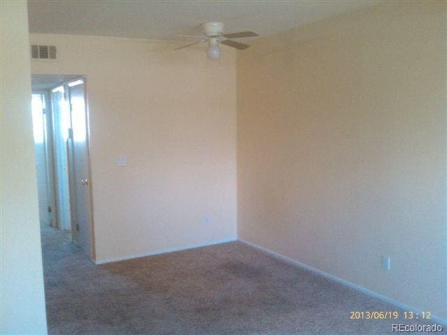 carpeted empty room with ceiling fan and baseboards