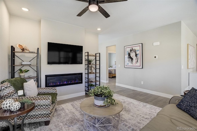 16277 Talons Bluff Ln, Monument, CO 80132 - living room with ceiling fan, wood finished floors, a glass covered fireplace, recessed lighting, and baseboards
