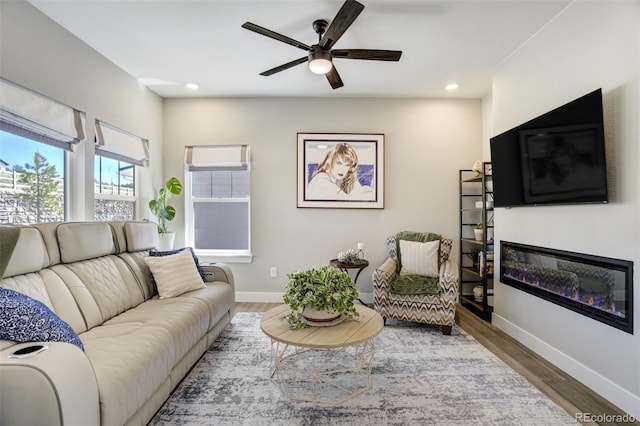 16277 Talons Bluff Ln, Monument, CO 80132 - living room featuring a glass covered fireplace, a ceiling fan, wood finished floors, baseboards, and recessed lighting