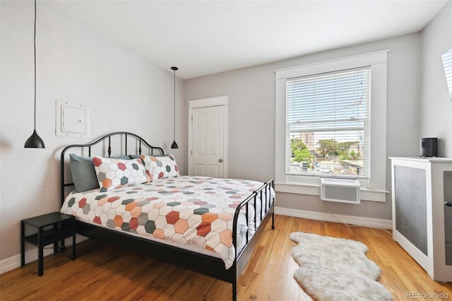 bedroom with a wall mounted air conditioner and hardwood / wood-style floors