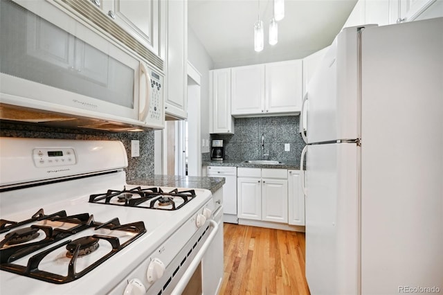 kitchen with light wood-type flooring, tasteful backsplash, white appliances, sink, and white cabinetry