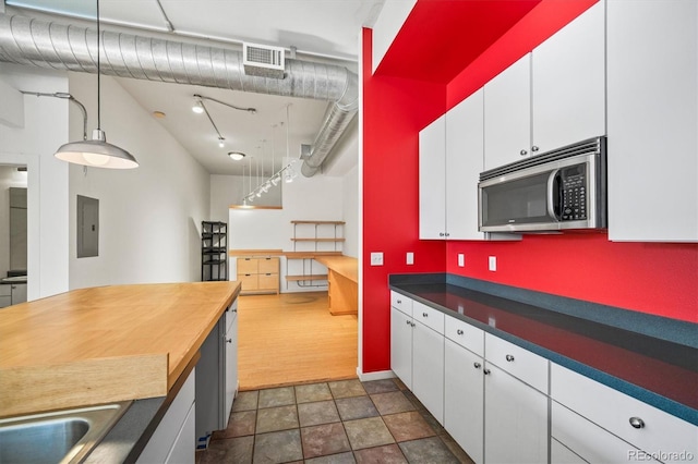 kitchen featuring sink, electric panel, white cabinetry, and decorative light fixtures