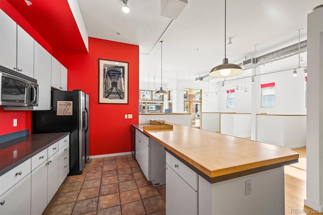 kitchen featuring white cabinetry, hanging light fixtures, and stainless steel appliances