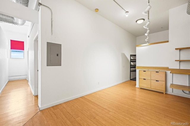 interior space with rail lighting, electric panel, and light hardwood / wood-style flooring