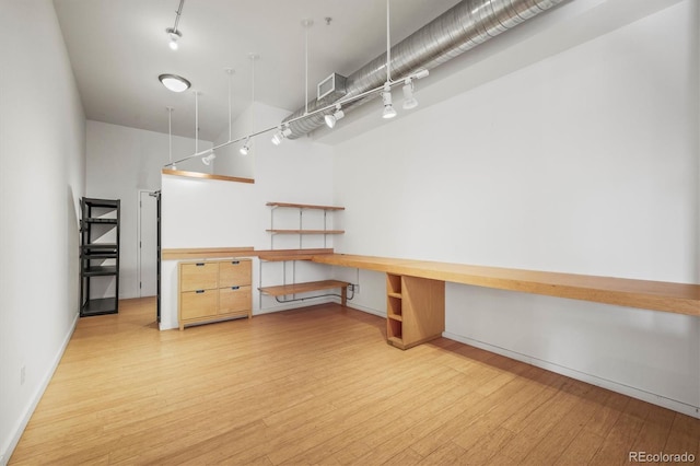 basement featuring light hardwood / wood-style floors and built in desk