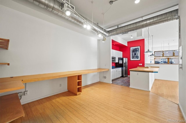 kitchen featuring light hardwood / wood-style floors, appliances with stainless steel finishes, white cabinetry, built in desk, and kitchen peninsula