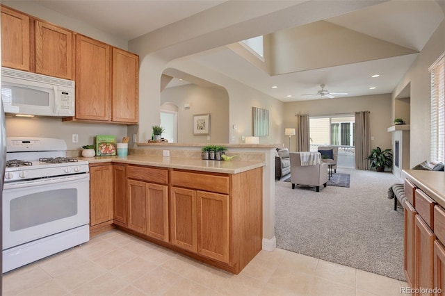 kitchen featuring lofted ceiling, white appliances, light carpet, kitchen peninsula, and ceiling fan