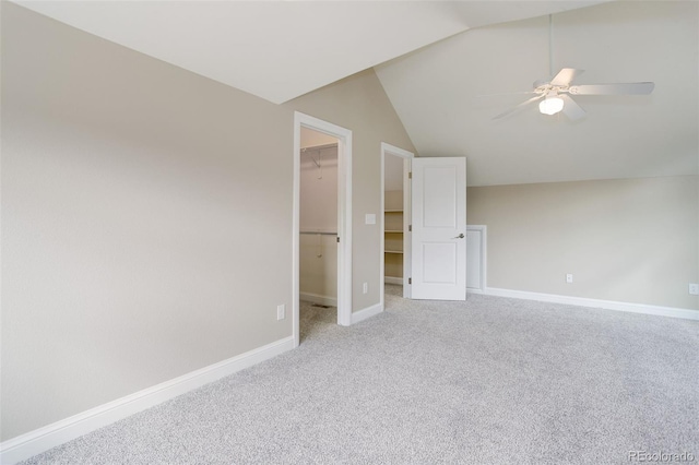 unfurnished bedroom with lofted ceiling, a walk in closet, carpet, ceiling fan, and a closet