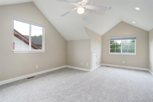 additional living space featuring light carpet, ceiling fan, vaulted ceiling, and a healthy amount of sunlight