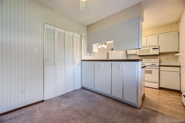 kitchen with white appliances, ceiling fan, white cabinets, and light colored carpet