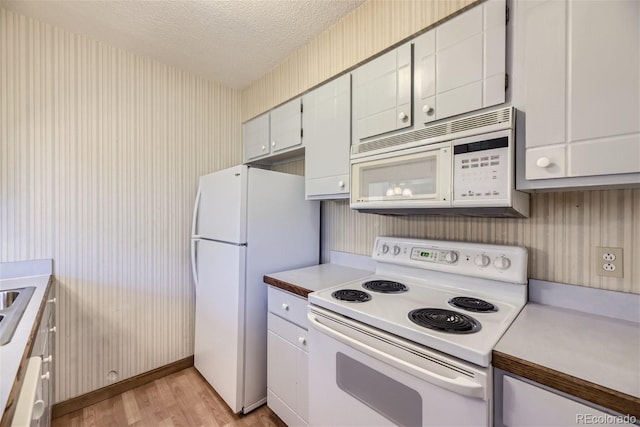 kitchen with white cabinetry, white appliances, a textured ceiling, and light hardwood / wood-style floors