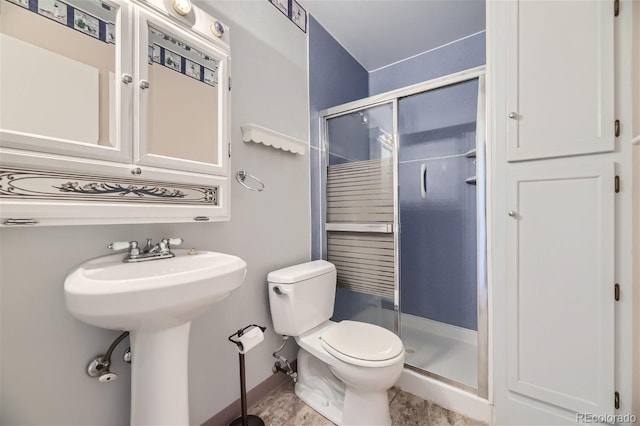 bathroom featuring sink, a shower with shower door, and toilet