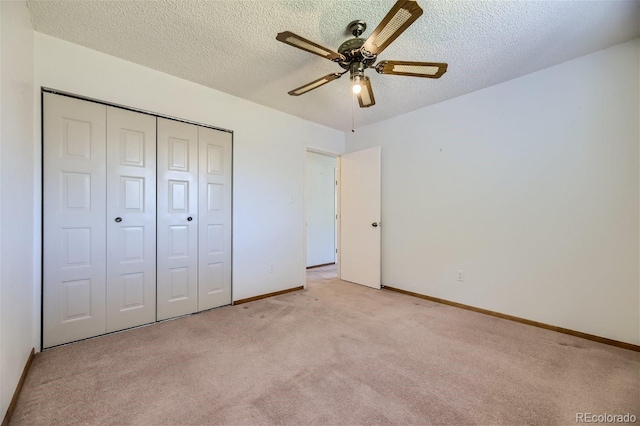 unfurnished bedroom with a textured ceiling, ceiling fan, a closet, and light colored carpet