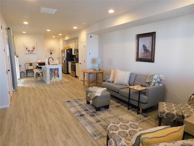 living room featuring light wood-type flooring and sink