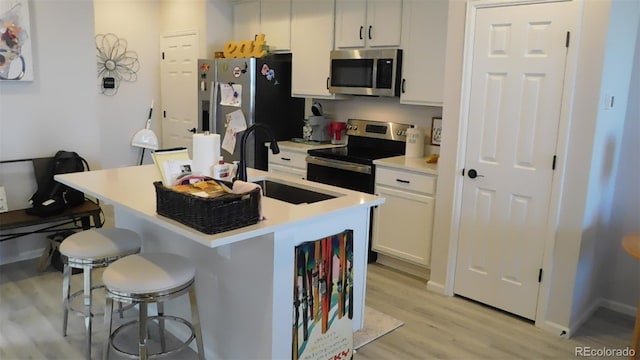 kitchen featuring white cabinets, a breakfast bar area, appliances with stainless steel finishes, and light hardwood / wood-style flooring