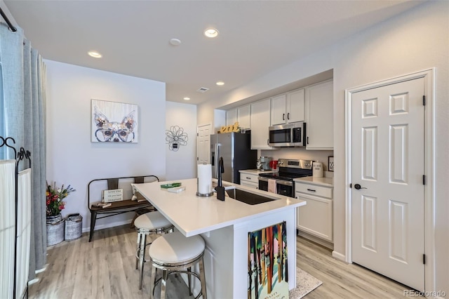 kitchen featuring a kitchen bar, an island with sink, white cabinets, and stainless steel appliances